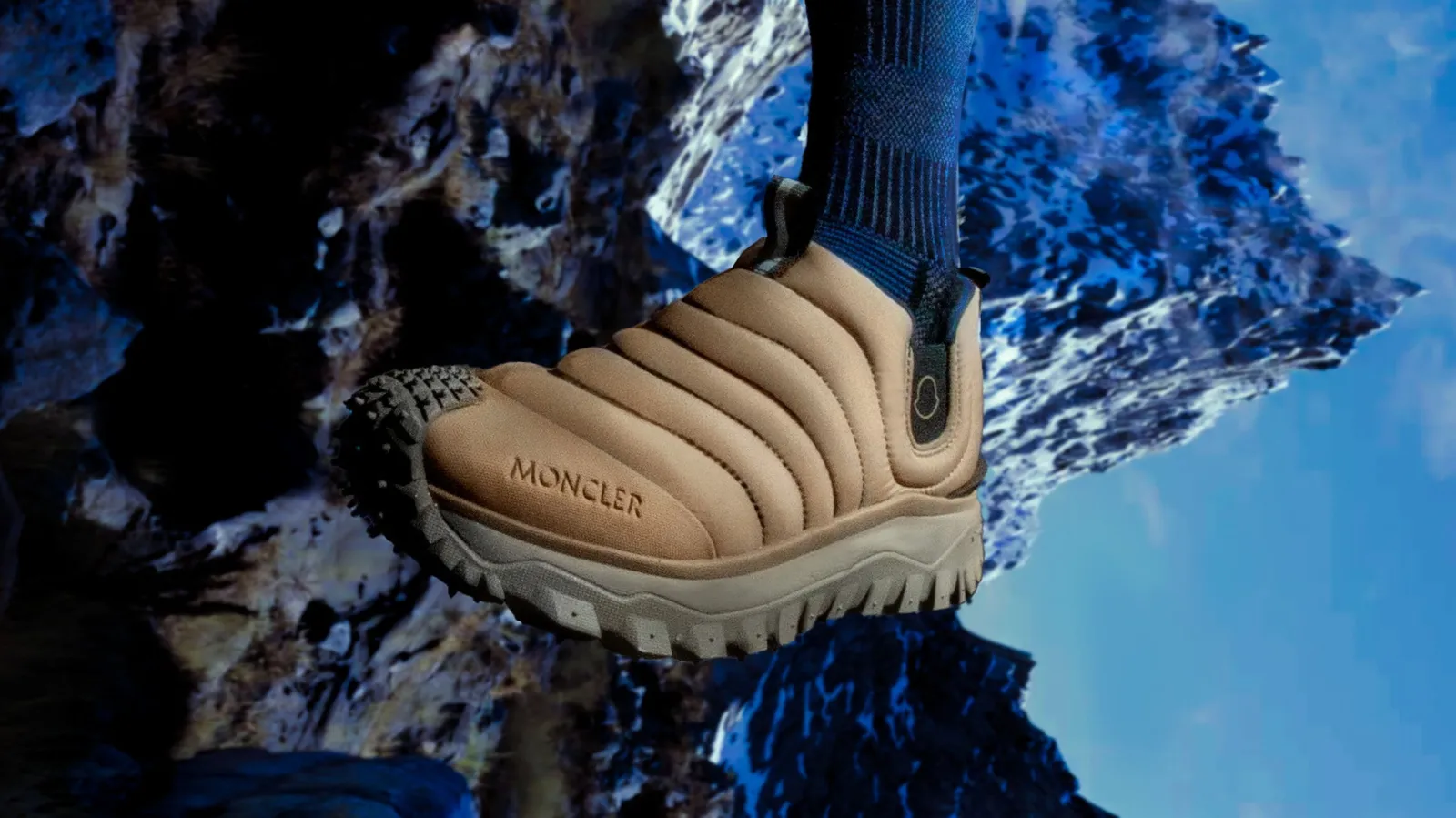 Sneaker Moncler sur des rochers enneigés, montagnes en arrière-plan