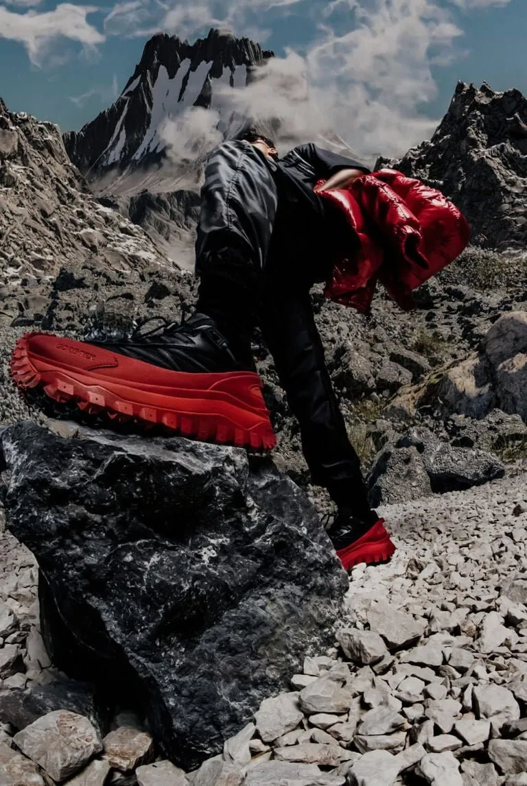 Campagne Moncler - grimpeur en chaussures de randonnée rouges sur un terrain rocheux
